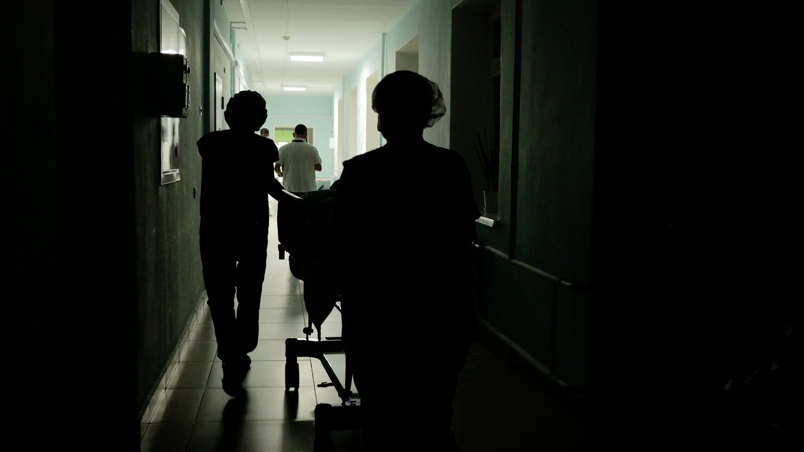 Medical team moving a patient gurney through a hospital corridor